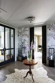 Vase of gladioli on round, antique table on animal-skin rug in elegant foyer