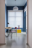 Blick ins Arbeitszimmer mit blauen Wänden und weißem Fensterrollo