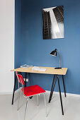 Schreibtisch mit rotem Stuhl vor blauer Wand im Arbeitszimmer