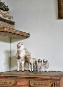 Vintage-style arrangement of old toy sheep on top of antique wooden trunk