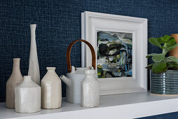 Ceramic vases and framed picture on shelf