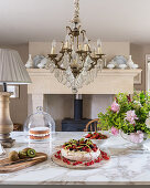 Kiwi and berry cake on marble countertop below French chandelier