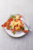 Scrambled eggs with tomatoes and crispy bacon