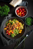 Yellow and green spaghetti with a colorful tomato and bacon sauce