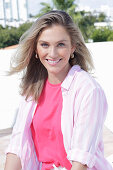 A young blonde woman wearing a pink top and a striped shirt