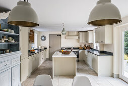 1940s Belgian oak armoire with painted factory lampshades in Quaker style kitchen with granite worktops