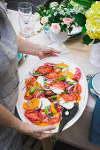 Person serviert sommerlichen Tomaten-Mozzarella-Salat