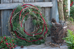 Wreath made of pine branches, clematis tendrils, and wool yarn, basket with pinecones