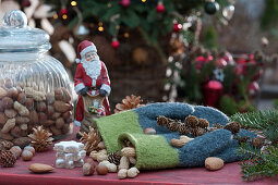 Arrangement with Father Christmas, mittens, nuts, pinecones, cinnamon stars, small wooden fir tree, fir branches, and blossoms of Christmas rose