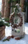 Lantern with wreath of larch cones, fir branch and Christmas tree decorations