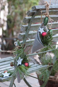 Homemade felt bags with Christmas tree decorations and pine branches hung on the back of a chair