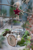 Hanging lantern with a self-made pendant made of a wooden disc, cones, fern leaves and a wooden star