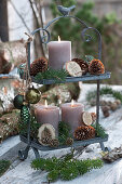 Metal étagère with candles, cones, fir branches, and Christmas tree decorations on a table
