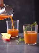 Frischer Obst-Gemüse-Saft wird in Gläser gegossen