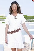 Langhaarige Frau in weißem Sommerkleid mit Gürtel