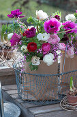 Spring bouquets of ranunculus, anemone, and broom in paper bags in a wire basket
