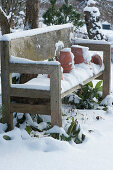 Wooden bench and clay pots in the snowy garden
