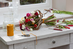 An unusual spring bouquet of ranunculus and dried stalks of Chinese silver grass lying on a work table