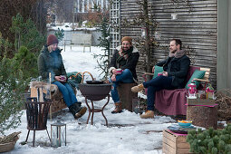 Friends sitting comfortably on the terrace with barbecue and fire basket