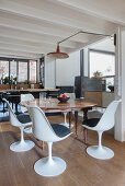 Dining area with antique wooden table and white modern chairs in a loft