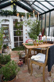 Suspended wreath with candles above dining table in conservatory decorated for Christmas