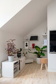 sideboard, shelves, and houseplants in a room with sloping roof