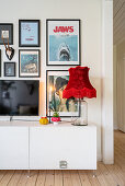 Old-fashioned red lampshade on a glass jar in front of a gallery of pictures