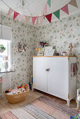 Old cupboard in vintage-style child's bedroom with floral wallpaper