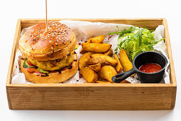 American chicken burger with potato wedges and tomato sauce