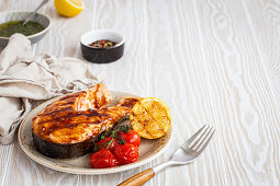 Grilled salmon steak glazed with teriyaki sauce, tomatoes and lemon
