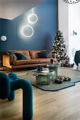 Leather sofa, Christmas tree and designer chair in the living room with a blue wall