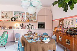 Table set for Christmas in front of a retro sideboard and fitted kitchen cabinets with pink fronts