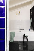 Glance into the bathroom with white wall tiles and black floor tiles