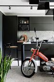 Motorrad im Wohnraum mit schwarzer Einbauküche