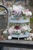 Metal etagere with pastel-colored bouquets of ranunculus and cuckoo campion 'Petit Henry' 'Petit Jenny', decorated with feathers and eggs