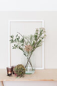 Hydrangea flower next to flowering branches in glass vase