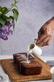 Pouring sugar icing over poppy seeds and lemon cake