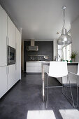 White cupboard and counter with bar stools in kitchen with concrete floor