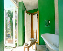 Frei stehende Badewanne und Paravent im Badezimmer mit grünen Wänden und Terrassenzugang