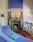 Blue couch in front of fireplace with blue chimney breast in living room