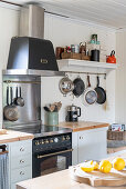 Oven with a stove top and extractor hood, shelf and hanging pots next to it
