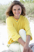 A young woman with long hair wearing a yellow jumper and trousers