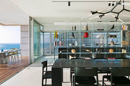 Black dining table and chairs next to open terrace in luxury penthouse