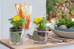 Easter terrace: small glasses with parsley as place cards with name tags, dandelion flowers and glass with vegetable sticks