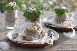 Easter plate decoration with watercress in jars, decorated with daisy blossoms and Easter eggs