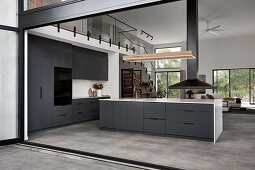 Black kitchen with island counter in open-plan interior with gallery level