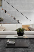 White sofa combination in high-ceilinged open-plan interior with staircase on back wall