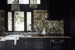 Fitted kitchen with dark cupboard fronts, tiles with tropical motif as splashback