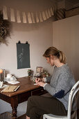 Woman sitting at old wooden table painting below DIY bunting