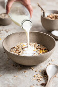 milk being poured in to a cereal bowl